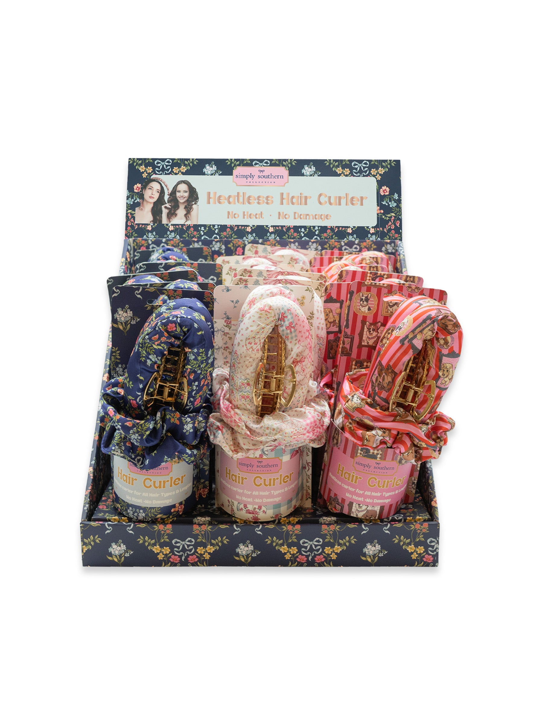 A retail display box containing three packaged necklaces, each wrapped in patterned fabric and labeled 'Necklace Hair Curler.' The display box has a floral navy header and base, and the necklaces inside are visible through the front window.