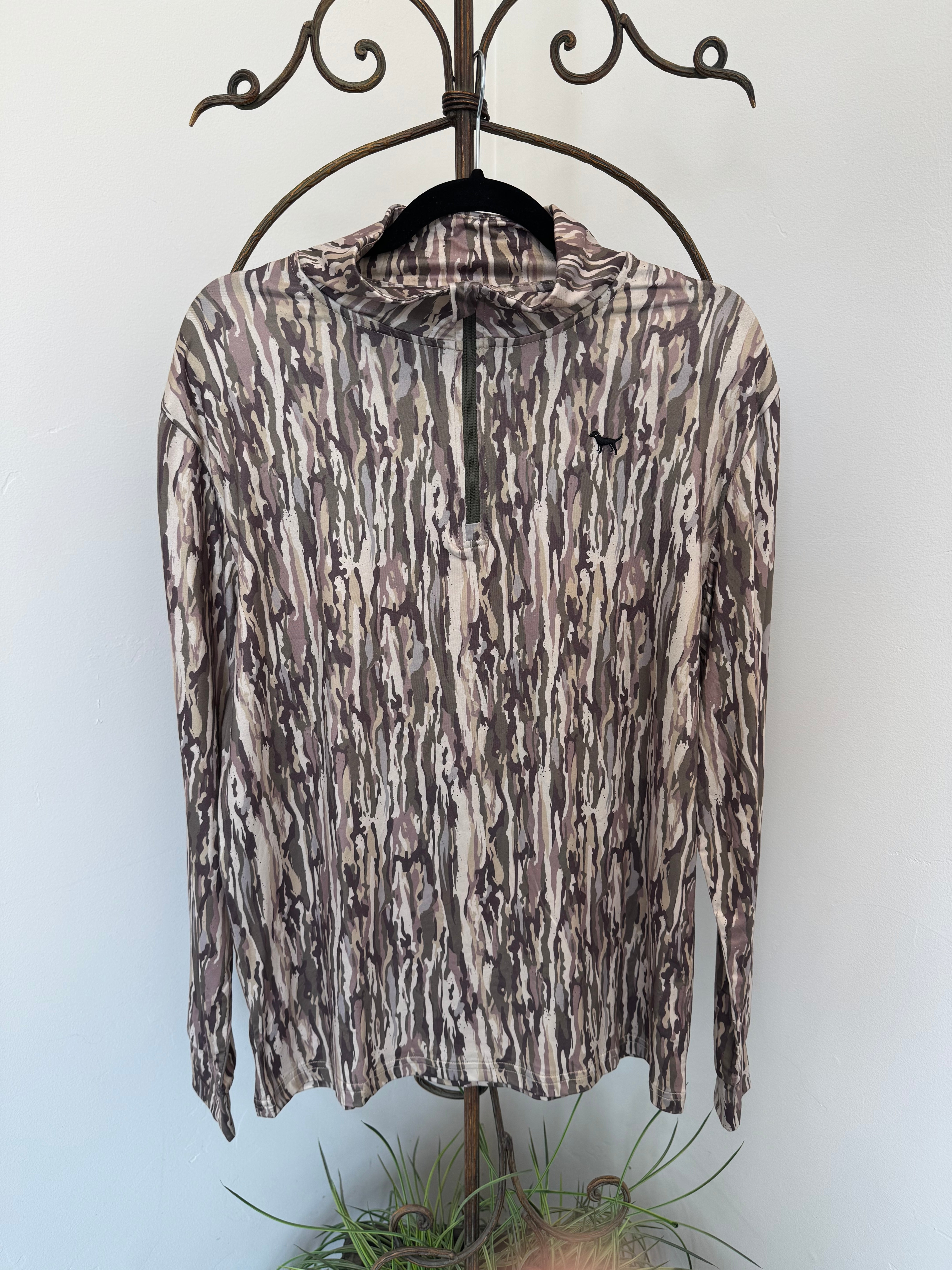 A long-sleeve quarter-zip pullover top with an abstract bark-like camouflage pattern in brown, beige, and gray, hanging on a black hanger from a decorative metal coat rack.