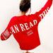 Person wearing a red sweatshirt with text on the back against a white background