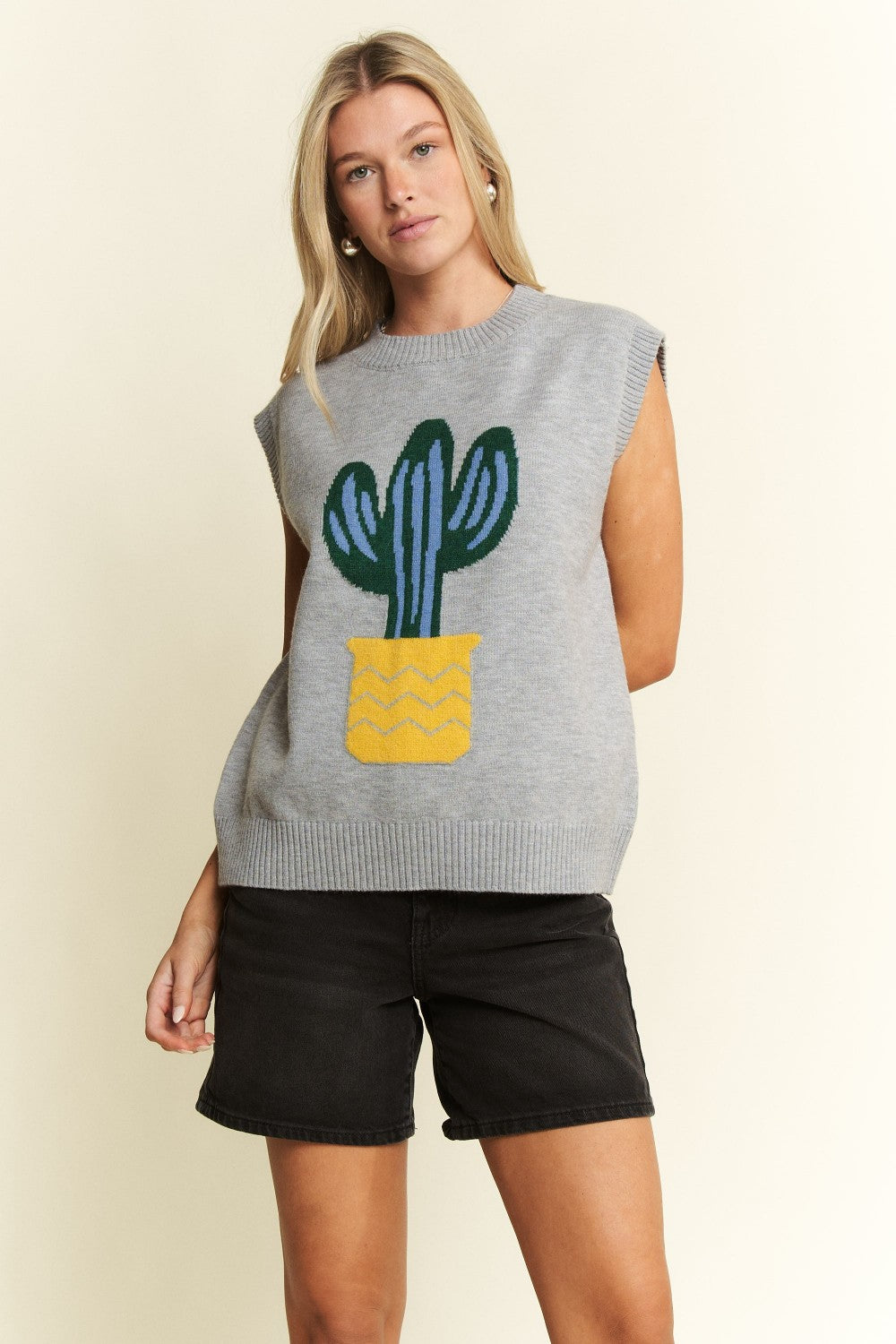 Woman wearing a sleeveless sweater with a cactus design on a beige background
